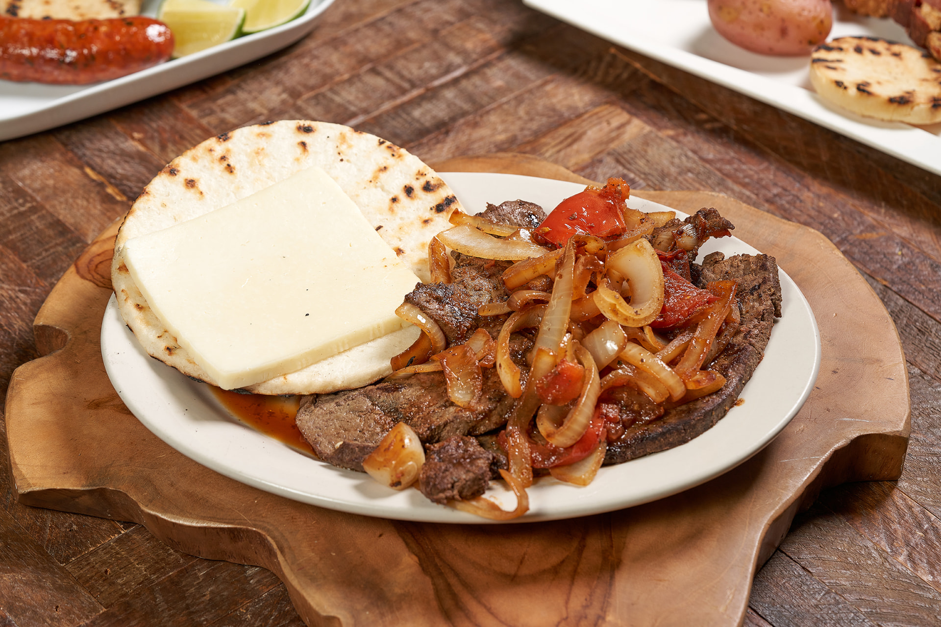 Bistec encebollado with grilled arepa and white cheese