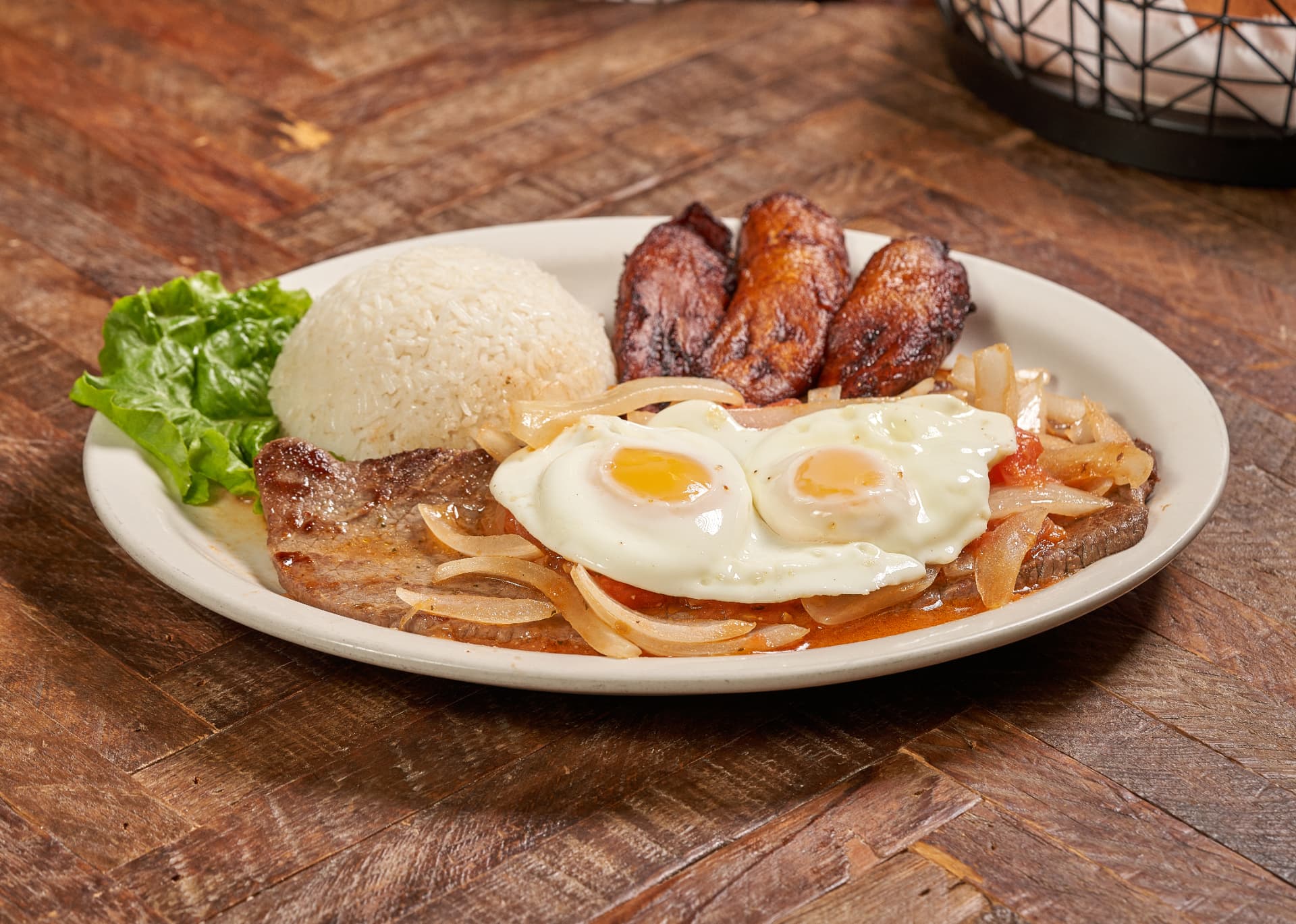 Steak with fried eggs, rice and sweet plantain
